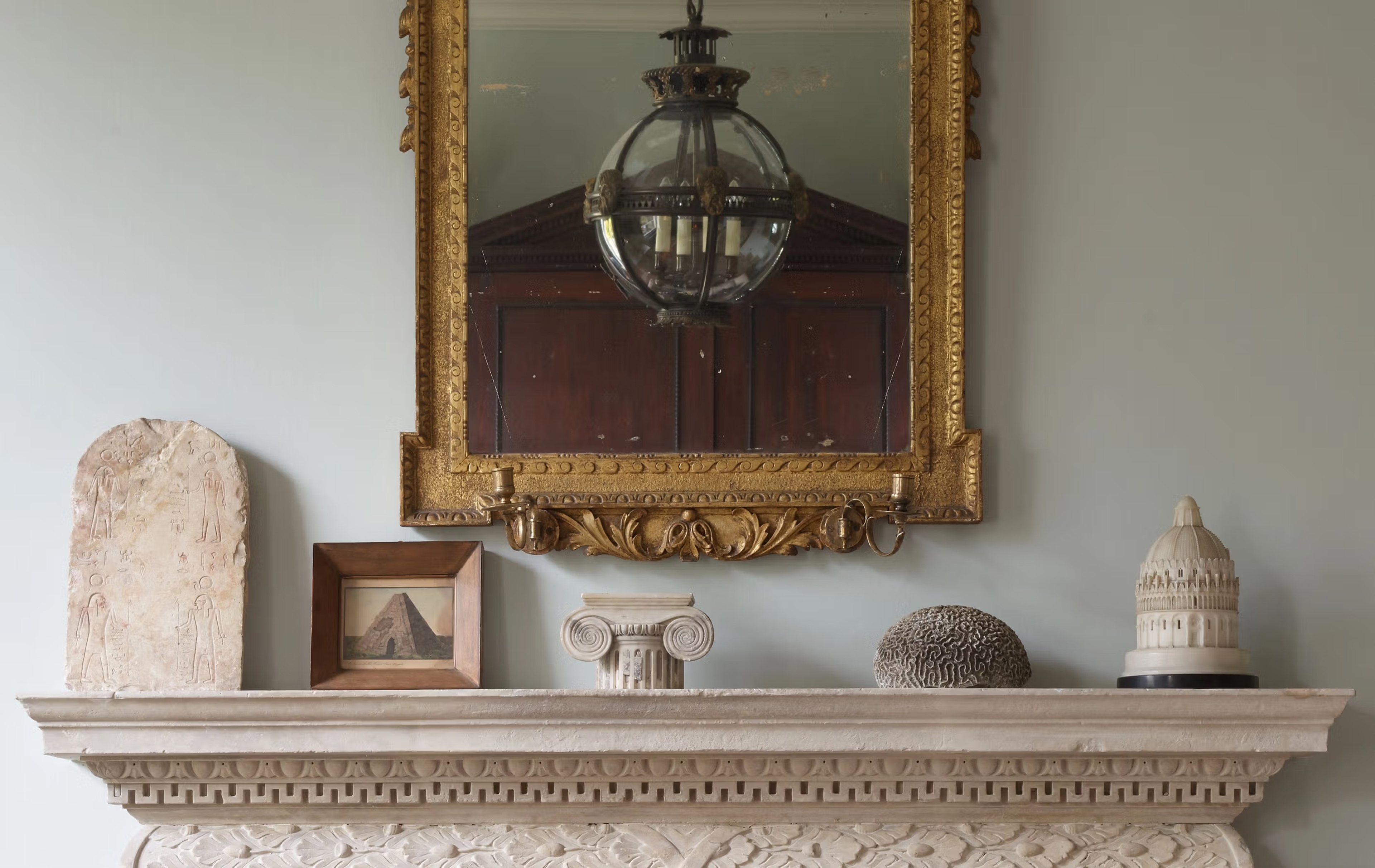 Jamb mantelpiece with gilded mirror, hanging lantern, and antiques
